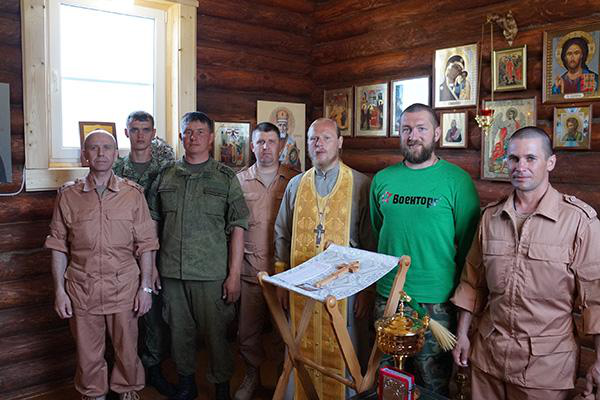 الكاهن إيليا أزارين بين جنود روس داخل الكنيسة الميدانية في قاعدة حميميم.png