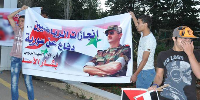 موالون يرفعون لافتة تظهر إقحام الأسد الرياضة في السياسة.jpg