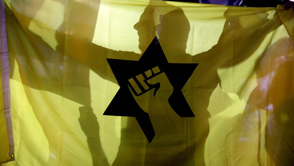 أحد أنصار اليمين المتطرف في إسرائيل يرفع علم حركة "كاخ" الفاشية في مظاهرة في القدس عام 2015 (الصحافة الإسرائيلية) 