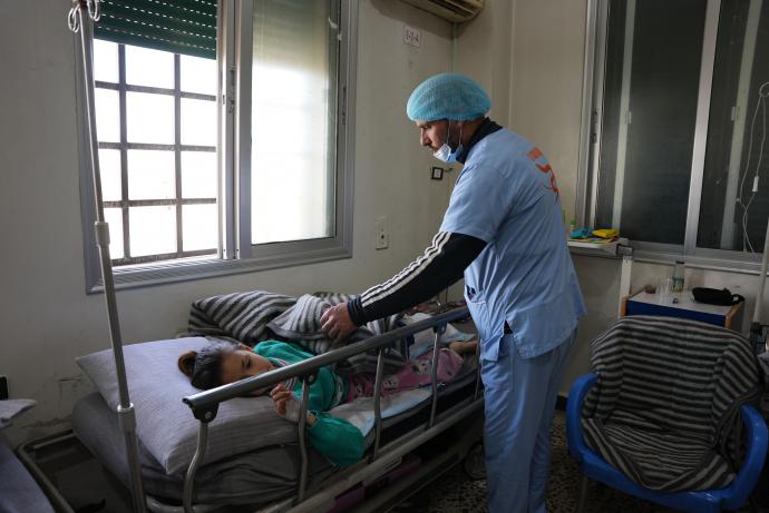 الممرض أحمد الشيخ يتفقد حال طفلة مصابة تتلقى العلاج في المشفى (تلفزيون سوريا)