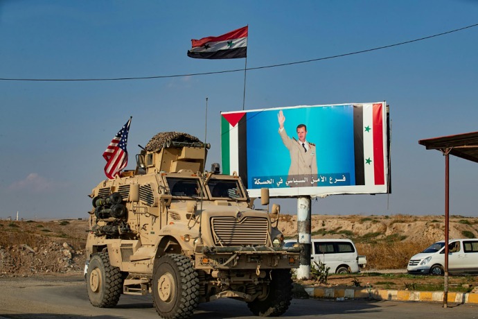 مدرعة أميركية عند نقطة تفتيش شمال شرقي سوريا بجانب صورة للرئيس بشار الأسد - AFP