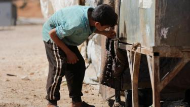 طفل يشرب الماء في مخيم للمهجرين شمالي إدلب - رويترز