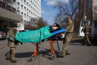 مسعفان ينقلان جندياً أوكرانياً جريحاً إلى أحد المشافي في كييف 24 آذار 2022