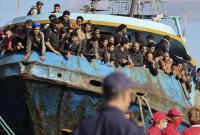 لاجئون ينظرون من قارب صيد متهالك بعد سحبه من قبل السلطات اليونانية إلى ميناء باليوكورا - AP