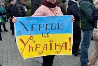 سيدة تحمل علم أوكرانيا ومكتوب عليه "خيرسون أوكرانية" (تويتر)