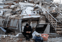 رجل يجلس على أنقاض منزله المدمر بفعل الزلزال في هاتاي التركية - GETTY