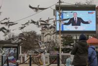 شاشة عرض في القرم تنقل خطاب فلاديمير بوتين أمام البرلمان الروسي (رويترز)