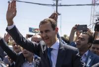 بشار الأسد يلوح لمؤيديه أمام مركز انتخابي في عام 2021