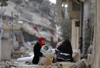 سوريتان تجلسان فوق أنقاض حيهما برفقة طفليهما