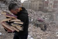 رجل يقبل نسخة من القرآن الكريم بعدما أخرجه من منزله المنهار في مدينة كهرمان مرعش جنوب تركيا في 6 آذار 2023 (رويترز)