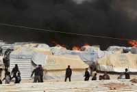 لاجئون سوريون يحاولون إطفاء حريق سابق في مخيم الزعتري - رويترز