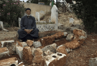 محمد حسن مسطو يجلس بجوار قبر شقيقه لطفي الذي قضى بغارة أميركية على قرية قورقنيا - AP