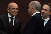 الرئيس التركي رجب طيب أردوغان يصافح وزير الخزانة والمالية محم شيمشك (رويترز)