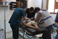 كادر طبي يُسعف طفل جريح بعد قصف النظام وروسيا على بلدة البارة (الدفاع المدني السوري)