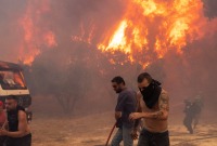 رجال إطفاء ومتطوعون يحاولون إطفال حرائق الغابات قرب أثينا - 22 آب 2023 (رويترز)