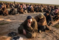 رجال يشتبه بانتمائهم إلى تنظيم الدولة ينتظرون تفتيشهم بعد مغادرتهم الباغوز في محافظة دير الزور (أ ف ب)