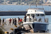 مهاجرون ينزلون من سفينة تابعة لخفر السواحل اليوناني في ميناء ميتيليني (رويترز)