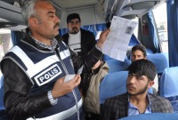 فرد من الشرطة يتحقق من إذن سفر أحد اللاجئين السوريين في تركيا (الأناضول)