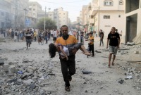 رجل فلسطيني يحمل طفلة جريحة من جراء قصف إسرائيلي على خان يونس جنوبي قطاع غزة - 14 تشرين الأول 2023 (رويترز)