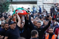 مشيعون يحملون جثمان أحد الفلسطينيين اللذين استشهدا برصاص جنود إسرائيليين في رام الله بالضفة الغربية التي تحتلها إسرائيل.