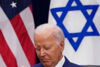 الرئيس الأميركي جو بايدن وخلفه علم بلاده وعلم إسرائيل