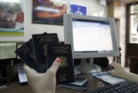 امرأة تحمل جوازات سفر سورية تعمل على الحاسوب في مكتب سفريات بدمشق (AFP)