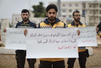متطوعون في الدفاع المدني يرفعون لافتات تطالب بمحاسبة النظام على استخدام الأسلحة الكيميائية