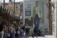 لافتة تحمل صورة رئيس النظام السوري بشار الأسد معلقة على جدار في سوق الحميدية في دمشق- أيلول 2023 (AFP)