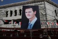 صورة لـ بشار الأسد على مبنى مدمر في مدينة دوما بريف دمشق (رويترز)