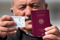عجوز تركي يحمل هويته الوطنية بيد وباليد الأخرى جواز سفره الألماني - المصدر: إيكونوميست