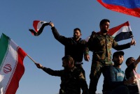مقاتلون يرفعون علم النظام السوري وإيران تنديداً بالغارات الأميركية على سوريا - نيسان 2018 (رويترز)