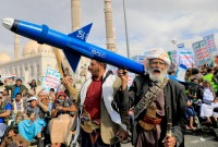 A Yemeni demonstrator carries a mock missile during a march in the capital, Sanaa, which is controlled by the Houthis, on March 8, 2024 (AFP)