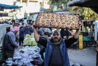 بائع يبيع الخبز الرمضاني التقليدي في سوق في اليوم الثالث من رمضان في أريحا، إدلب، سوريا في 13 مارس/آذا