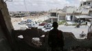 عنصر من قوات النظام يراقب المارّة من داخل بناء مهدّم في درعا البلد (أرشيفية/AFP)