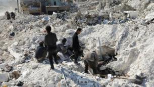 أشخاص يبحثون تحت أنقاض المباني المتضررة من الزلزال في بلدة حارم بريف إدلب (رويترز)