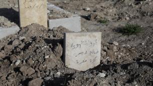منظر يظهر شاهد قبر كتب عليه بالعربية "فتاة صغيرة مجهولة الهوية ترتدي سترة خضراء" داخل مقبرة في بلدة جندرس