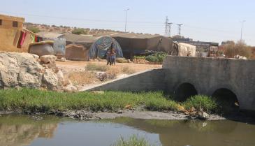 مخيم على جانب مجرى للصرف الصحي في ريف حلب (الدفاع المدني)