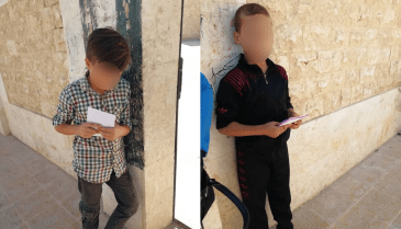 طفلان يوزعان منشورات ترويجية لصالح مرشح عن مجلس محافظة حلب في انتخابات الإدارة المحلية (فيسبوك/رضا الباشا)