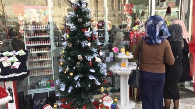 by_abdelhakam_ziyad._a_mosque_is_reflected_in_the_window_of_the_cosmetics_shop_outside_which_stands_a_decorated_chrstmas_tree.jpg