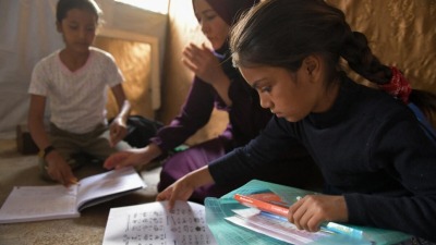 ابنتا اللاجئة السورية ماجدة وهما تقومان بحل واجباتهما المدرسية في المأوى الذي تقيمان فيه