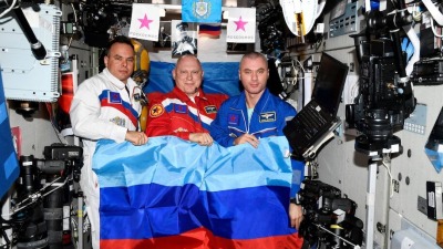 رواد الفضاء الروس أوليغ آرتيمييف ودينيس ماتفييف وسيرغي كورساكوف وهم يحملون علم دولة لوهانسك في محطة الفضاء الدولية بتاريخ 4 تموز 2022 