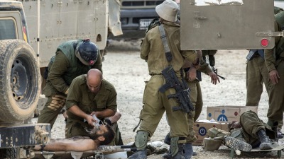 جنود إسرائيليون يجليون رفاقهم الجرحى في منطقة انتشار للجيش بالقرب من غزة - AFP