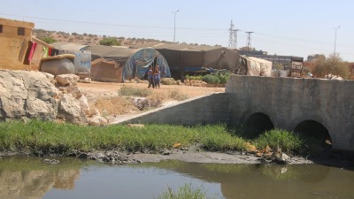 مخيم على جانب مجرى للصرف الصحي في ريف حلب (الدفاع المدني)