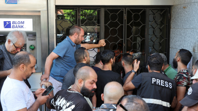 أشخاص يقفون خارج فرع لبنك لبنان والمهجر بمنطقة الطريق الجديدة في بيروت اليوم الجمعة (رويترز)