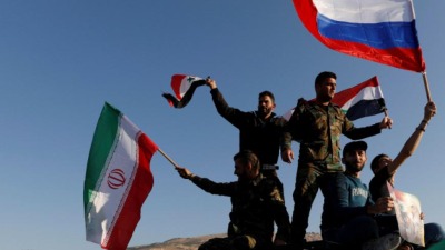 عساكر تابعين للنظام السوري ومدنيين موالين لبشار الأسد يرفعون أعلام النظام وروسيا وإيران (رويترز)