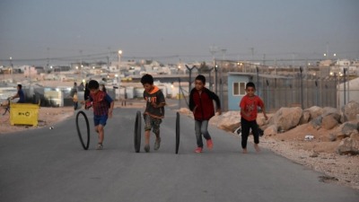 أطفال سوريون يلعبون بعجلات مطاطية في مخيم الزعتري بالأردن (الجزيرة)