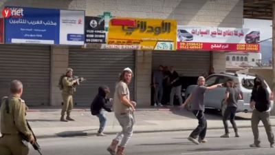 لقطة شاشة من فيديو نشرته "يديعوت احرونوت" يظهر فيه هجوم مستوطنين بحماية الجنود الإسرائيليين على أصحاب المحلات الفلسطينيين وممتلكاتهم، بلدة حوارة جنوبي نابلس، 13 تشرين الأول/أكتوبر 2022
