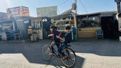 طفلان سوريان يركبان دراجة في الشارع الرئيسي بمخيم الزعتري في الأردن