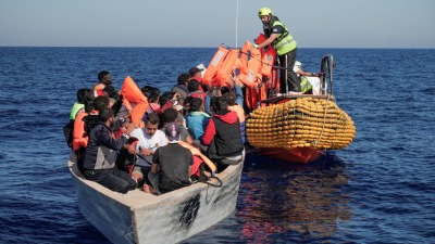 أعضاء من منظمات "أوشن فايكنغ" يقدمون سترات نجاة للاجئين على متن قارب مكتظ في البحر الأبيض المتوسط - 25 تشرين الأول 2022 (رويترز)