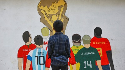 طفل ينظر إلى لوحة جدارية في بنغلاديش تحتفي بمونديال قطر 2022 (رويترز)